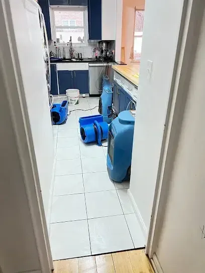 Air movers and a dehumidifier drying a kitchen floor
