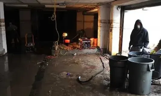 Crew clearing flood water and debris from a flooded ground floor after a storm