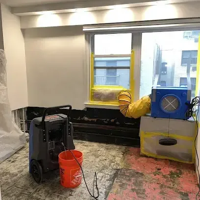 Drying equipment running in a water-damaged room with flooring pulled back