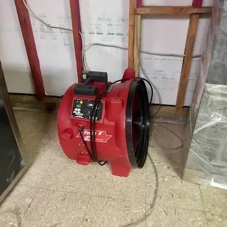 Red air mover drying a room with opened lower walls and plastic sheeting