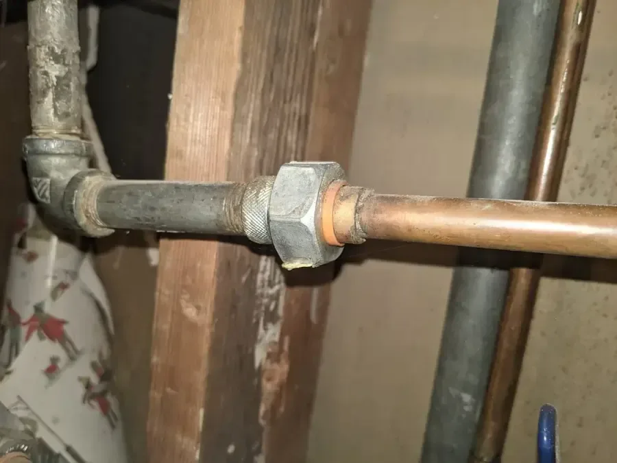 Old galvanized pipe joined to copper supply pipe inside an opened wall cavity