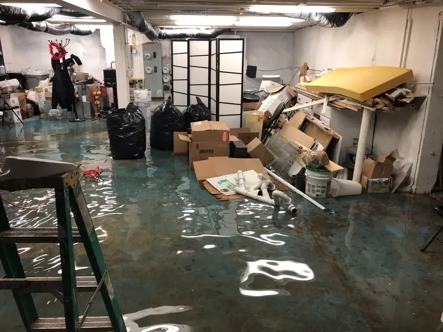 A technician in protective gear cleaning up a black water backup