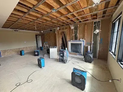 Air movers and a dehumidifier drying a room with the ceiling and flooring opened